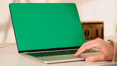 Cropped view of blurred woman using laptop with green screen at home  clipart