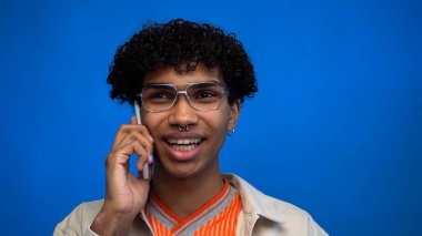 Gülümseyen Afrikalı Amerikalı adam mavi telefondan konuşuyor. 