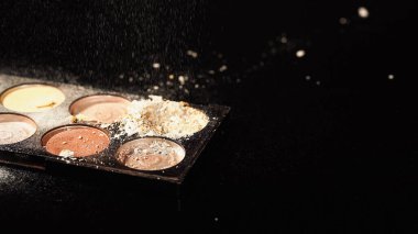 Siyah arkaplanda paletin üzerine dökülen yüz pudrasının görüntüsünü kapat 