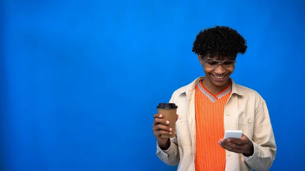 Sorrindo Afro Americano Segurando Bebida Takeaway Usando Smartphone Fundo Azul — Fotografia de Stock