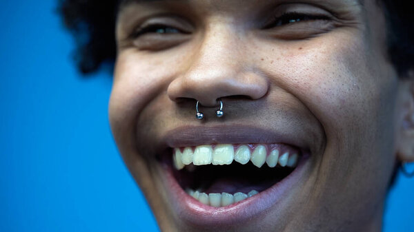 Закройте обзор возбужденному африканскому мужчине, который смотрит в сторону и смеется в одиночестве на голубом фоне 