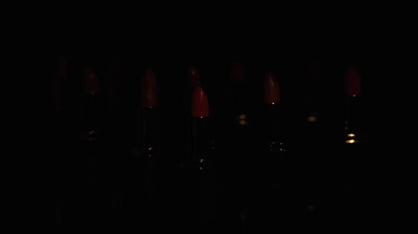 Red lipsticks in darkness on black background with copy space