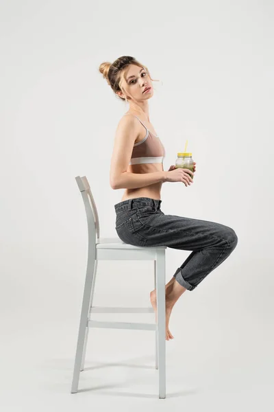 Slender Woman Sports Top Jeans Holding Smoothie While Sitting White — Stock Photo, Image