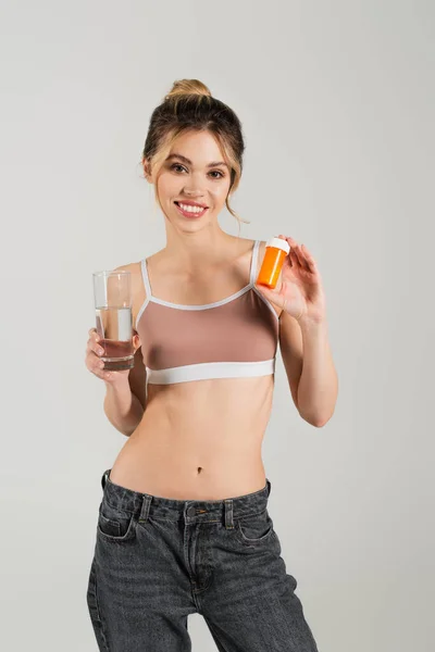 Glückliche Frau Sporttop Mit Glas Reinen Wassers Und Vitaminen Isoliert — Stockfoto