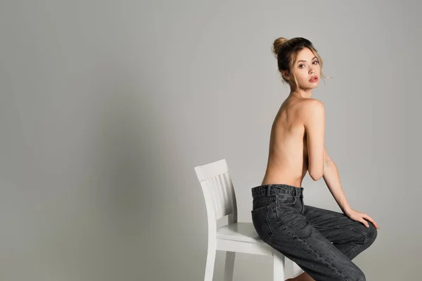 Ung Halvnaken Kvinna Jeans Sitter Vit Stol Och Tittar Kameran — Stockfoto