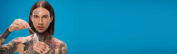 Jovem Tatuado Homem Segurando Garrafa Com Soro Hidratante Isolado Azul — Fotografia de Stock
