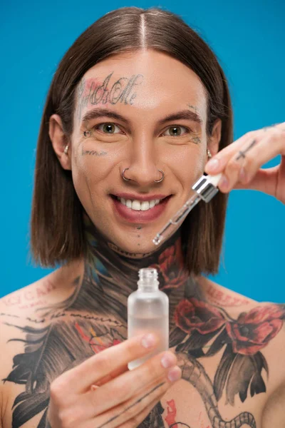 Hombre Sonriente Tatuado Sosteniendo Botella Con Suero Hidratante Aislado Azul — Foto de Stock