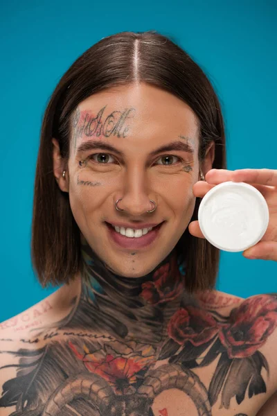 Pozitivní Mladý Muž Drží Kontejner Kosmetickým Krémem Izolované Modré — Stock fotografie
