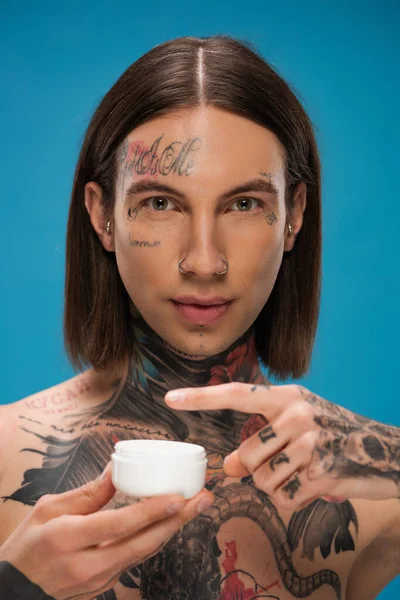 Tetovaný Mladý Muž Drží Kontejner Obličejovým Krémem Izolované Modré — Stock fotografie