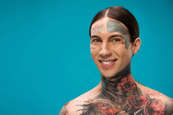 Hombre Joven Tatuado Con Máscara Arcilla Cara Sonriendo Aislado Azul — Foto de Stock