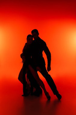 Kırmızı arka planda tango yapan balo dansçılarının silueti. 