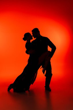 Side view of silhouette of couple dancing tango on red background  clipart