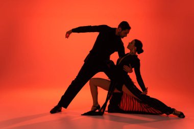 Kırmızı arka planda profesyonel dansçı kadını kucaklıyor. 