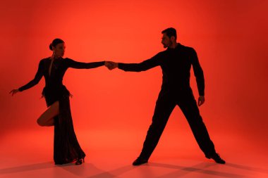 Silhouette of ballroom dancers holding hands on red background with shadow  clipart