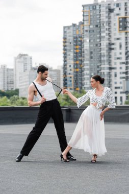 Topuklu ayakkabılı esmer dansçı çatıda partneriyle koreografi yapıyor. 