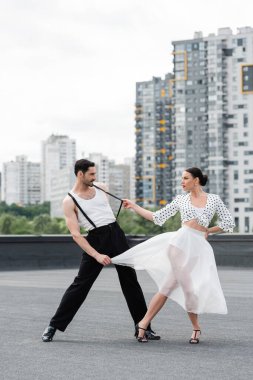 Topuklu ayakkabıyla dans eden ve çatıda dans eden şık dansçının yan görüntüsü. 