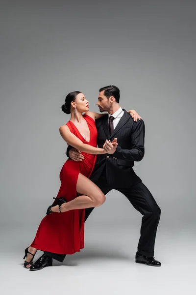 Side view of man dancing tango with elegant partner on grey background
