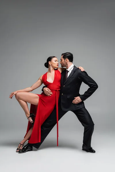 Elegancka Kobieta Sukience Patrząc Partnera Podczas Tańca Tango Szarym Tle — Zdjęcie stockowe