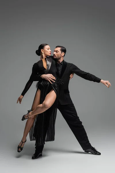 Dançarinos Profissionais Salão Trajes Pretos Realizando Tango Fundo Cinza — Fotografia de Stock