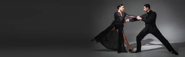 在灰色背景下 带着阴影和横幅跳舞时 舞厅舞者手牵手的侧视图 — 图库照片
