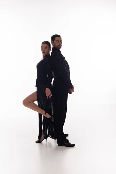 Pair of professional dancers standing back to back on white background