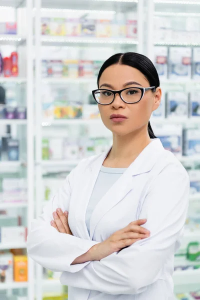 Asiatischer Apotheker in Brille mit verschränkten Armen im Drogeriemarkt — Stockfoto