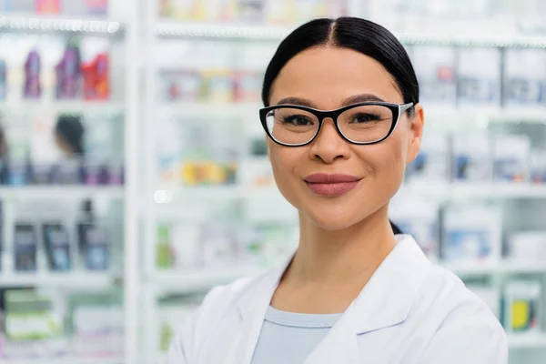 Asiatique pharmacien dans lunettes sourire tout en regardant caméra — Photo de stock