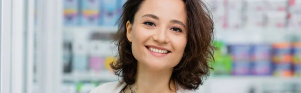 Mujer alegre y tatuada sonriendo en la farmacia, pancarta - foto de stock