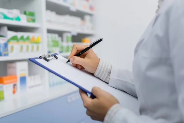 Vista cortada do farmacêutico em branco casaco escrito na área de transferência — Fotografia de Stock