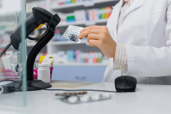 Ausgeschnittene Ansicht eines Apothekers mit Blisterpackung in der Nähe eines Scanners in der Drogerie — Stockfoto