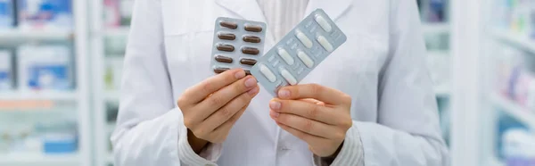 Cropped view of apothecary holding blister packs with medication, banner — Stock Photo