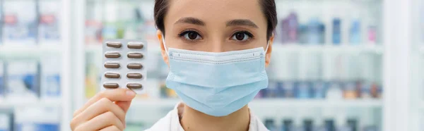 Apotheke in medizinischer Maske mit Blisterverpackung mit Medikamenten, Banner — Stockfoto