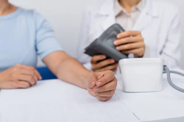 Ausgeschnittene Ansicht eines verschwommenen Arztes im weißen Kittel, der Tonometer in Patientennähe hält — Stockfoto