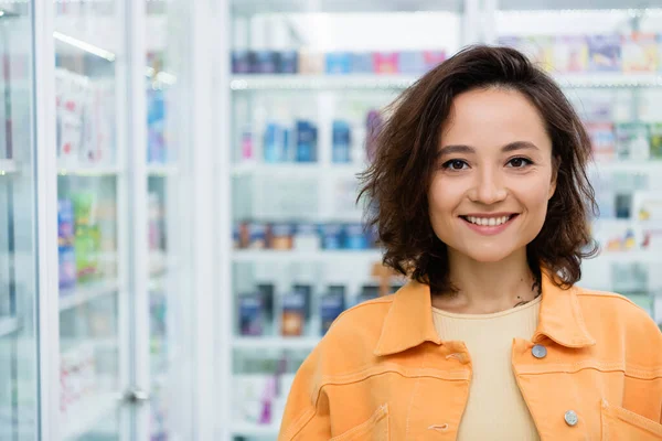 Счастливая и татуированная женщина, улыбающаяся в аптеке — стоковое фото