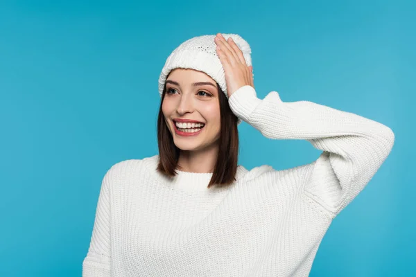 Positive woman in white hat and sweater isolated on blue — Stock Photo