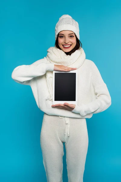 Mulher sorridente em roupas brancas de malha segurando tablet digital com tela em branco isolado em azul — Fotografia de Stock