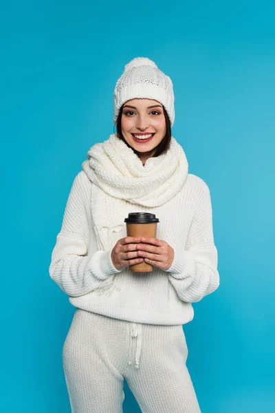 Mulher bonita em cachecol de malha e chapéu segurando café para ir isolado em azul — Fotografia de Stock