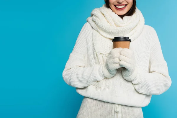 Vista cortada de mulher sorridente em cachecol e luvas segurando café para ir isolado em azul — Fotografia de Stock