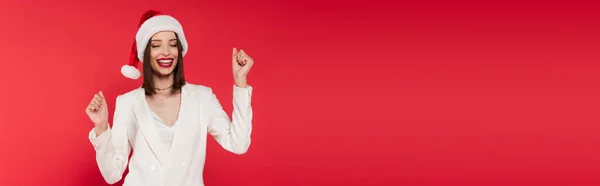 Brunette woman in santa hat showing yes gesture isolated on red, banner — Stock Photo