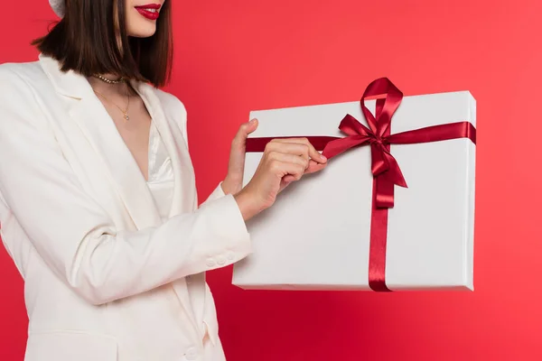 Cropped view of woman with red lips holding present isolated on red — Stock Photo