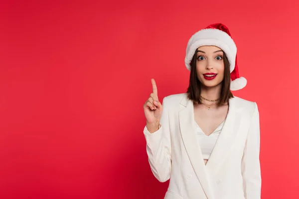 Aufgeregte Frau mit Weihnachtsmütze und Idee auf Rot — Stockfoto