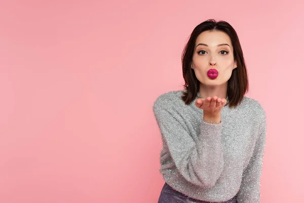 Mulher bonita em suéter quente soprando beijo de ar isolado em rosa — Fotografia de Stock