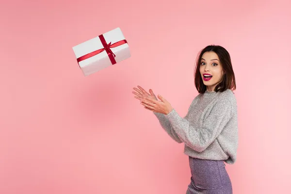 Femme élégante excitée jetant boîte cadeau isolé sur rose — Photo de stock