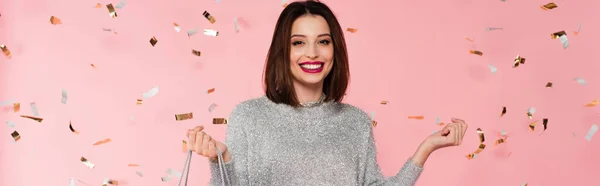 Positive Frau im Pullover mit Einkaufstasche unter Konfetti auf rosa Hintergrund, Banner — Stockfoto