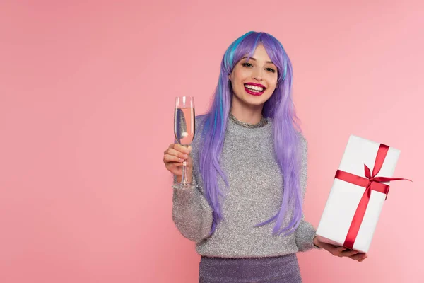 Stilvolle Frau mit gefärbten Haaren hält Champagner und Geschenkbox isoliert auf rosa — Stockfoto