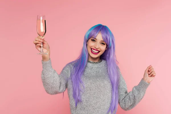 Mulher elegante positivo com cabelo tingido segurando champanhe isolado em rosa — Fotografia de Stock