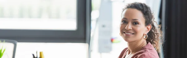 Sorridente donna d'affari afroamericana che guarda la telecamera in ufficio, striscione — Foto stock