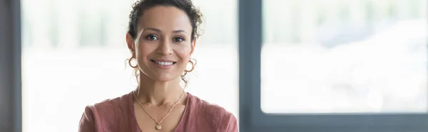 Positive african american businesswoman looking at camera in office, banner — Stock Photo