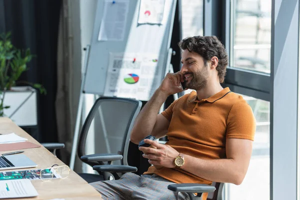 Geschäftsmann telefoniert mit Smartphone und hält Imbissgetränk am Arbeitstisch — Stockfoto