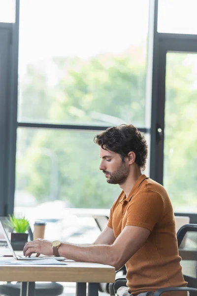 Side view of businessman using laptop on working table in office — Stock Photo